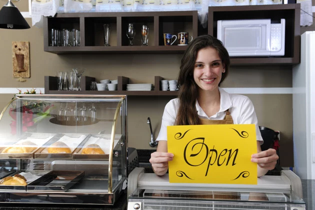 owner of a cafe showing open sign