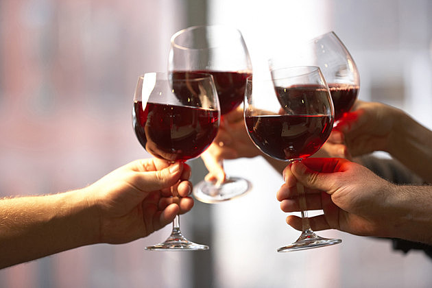 Close-up of four people's hands toasting with wine glasses