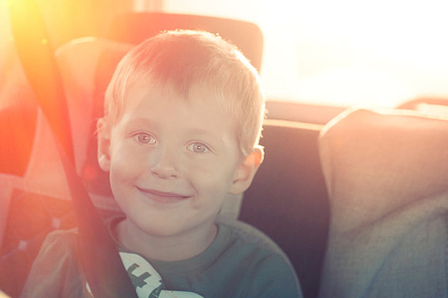 Cheerful child with buttoned belt in a car on a sunset